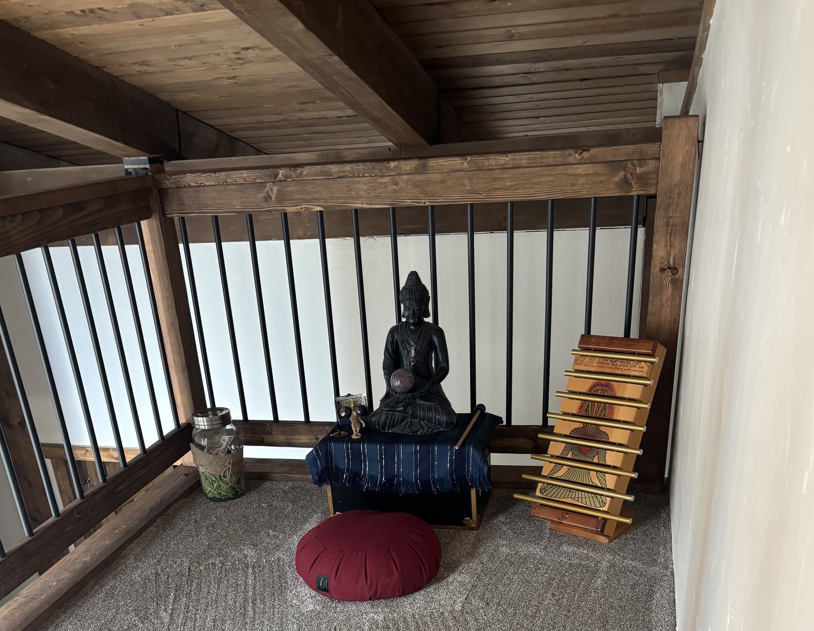 A quiet corner set up for reflection, with a Buddha statue and meditation cushion